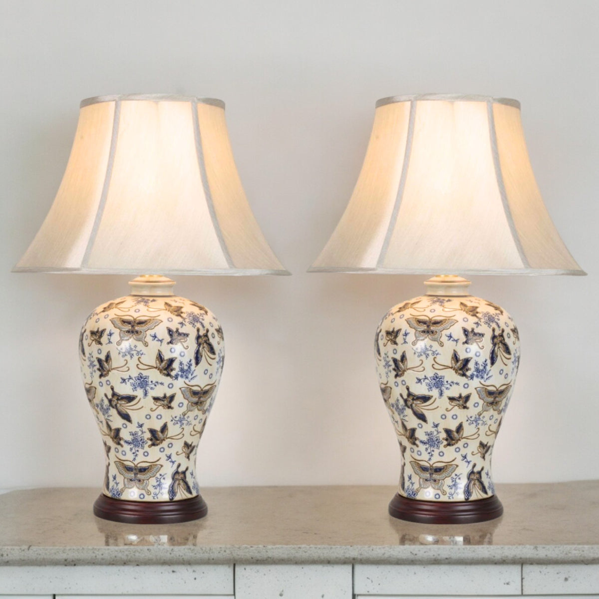 Pair of ivory porcelain table lamps with blue and silver butterflies and faux silk shades