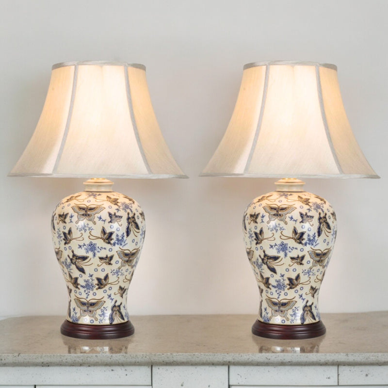 Pair of ivory porcelain table lamps with blue and silver butterflies and faux silk shades