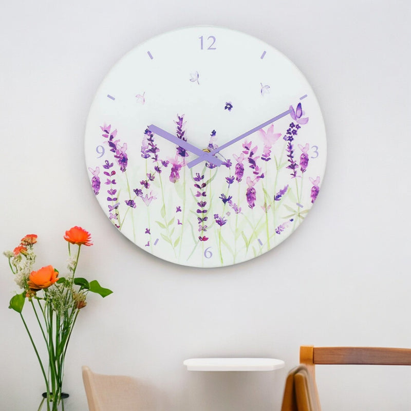 Round lavender glass wall clock with purple flowers and hands, displayed above a wooden sideboard