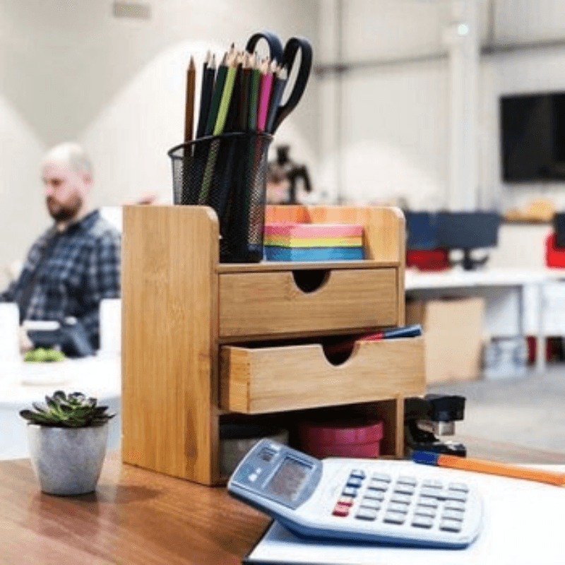 Bamboo desktop organiser holding stationery, with two drawers partly open