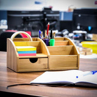 Bamboo desk tidy holding pens, sticky notes and tape on an office desk