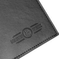 Stitched edge and embossed maker's mark on a black placemat