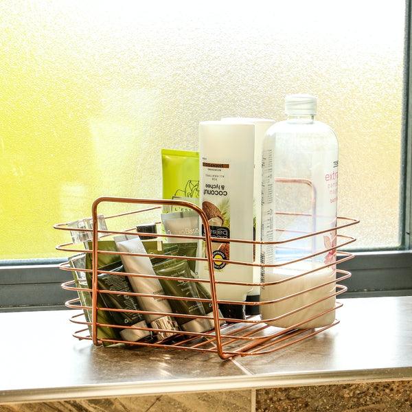 Rose gold basket holding toiletries on a bathroom windowsill