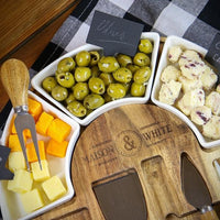 Round acacia cheese board served with cheese, olives and slate labels