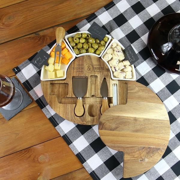 Overhead view of cheese board with three ceramic dishes and serving tools
