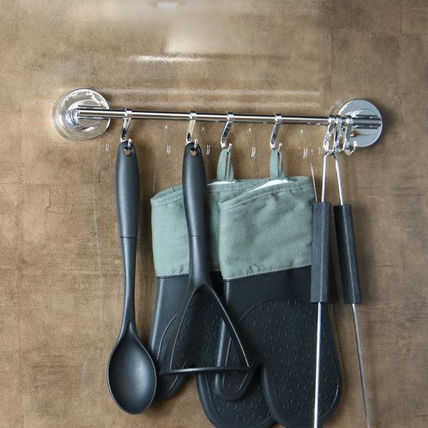 Wall-mounted suction rail holding utensils and a cloth