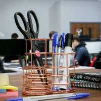 Rose gold desk tidy filled with stationery on an office desk