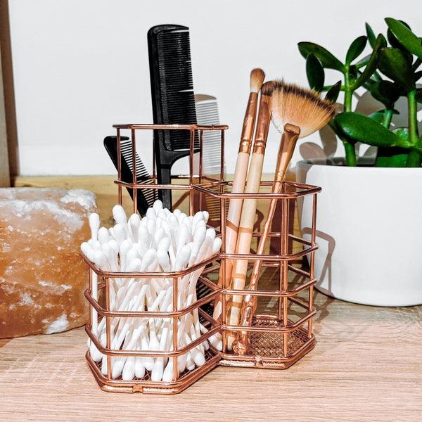 Rose gold organiser holding makeup brushes, cosmetics and cotton buds