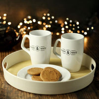 Round tray holding two mugs and a plate of biscuits