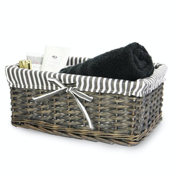 Medium grey wicker basket with striped liner holding toiletries and a towel