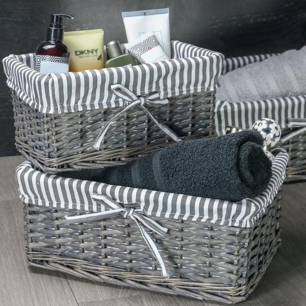 Grey wicker baskets holding towels and toiletries in a bathroom