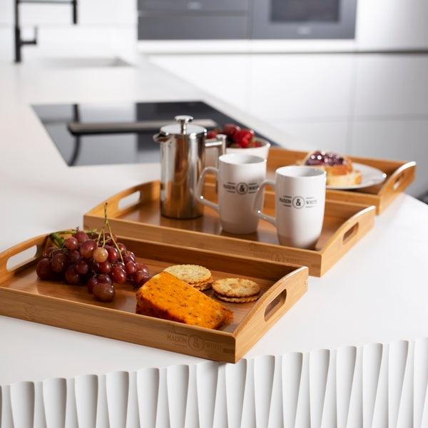 Bamboo serving trays with drinks and snacks on a kitchen counter
