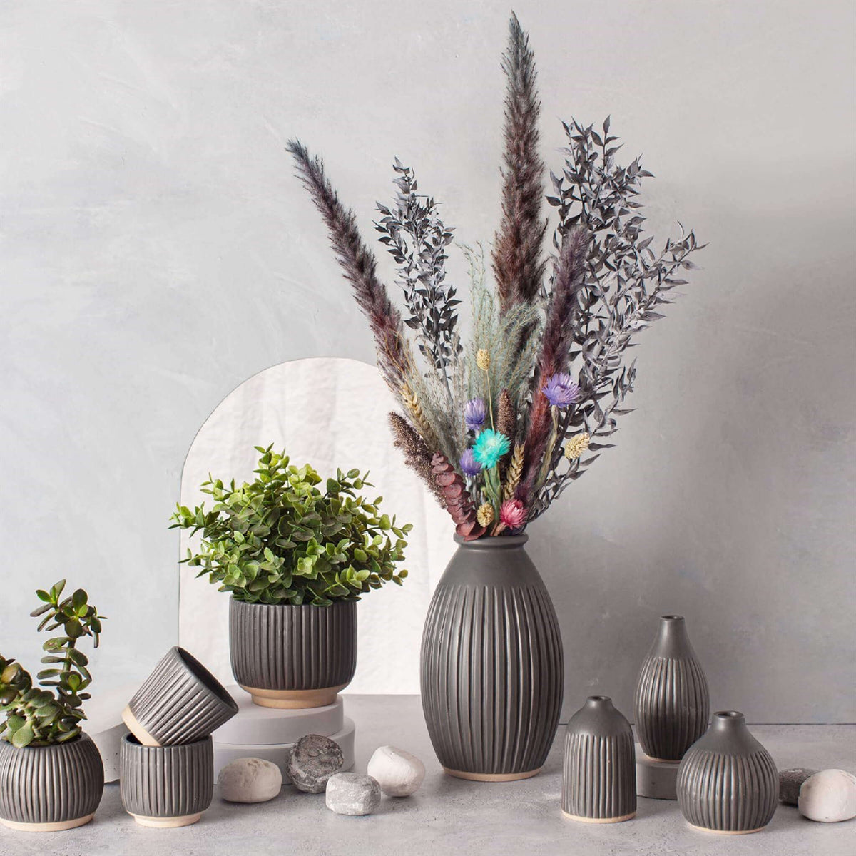 Large black grooved vase styled with dried flowers alongside other decorative vases