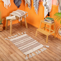 Nomad tassel rug styled on a wooden floor beside small stools