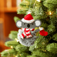 Festive koala ornament with fluffy grey body, Santa hat and striped scarf hanging on a Christmas tree