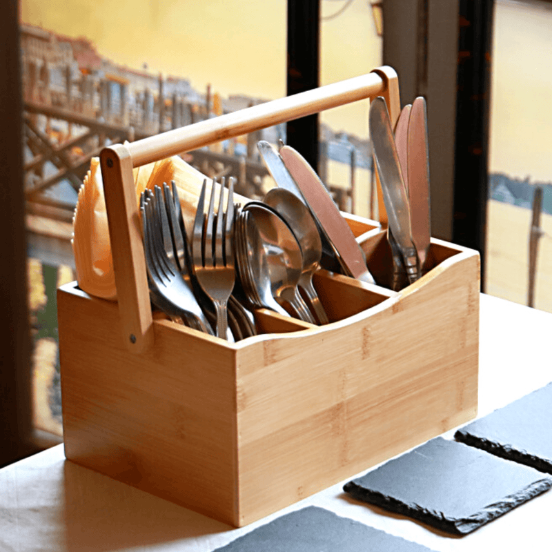 Bamboo cutlery caddy holding utensils beside a dining table