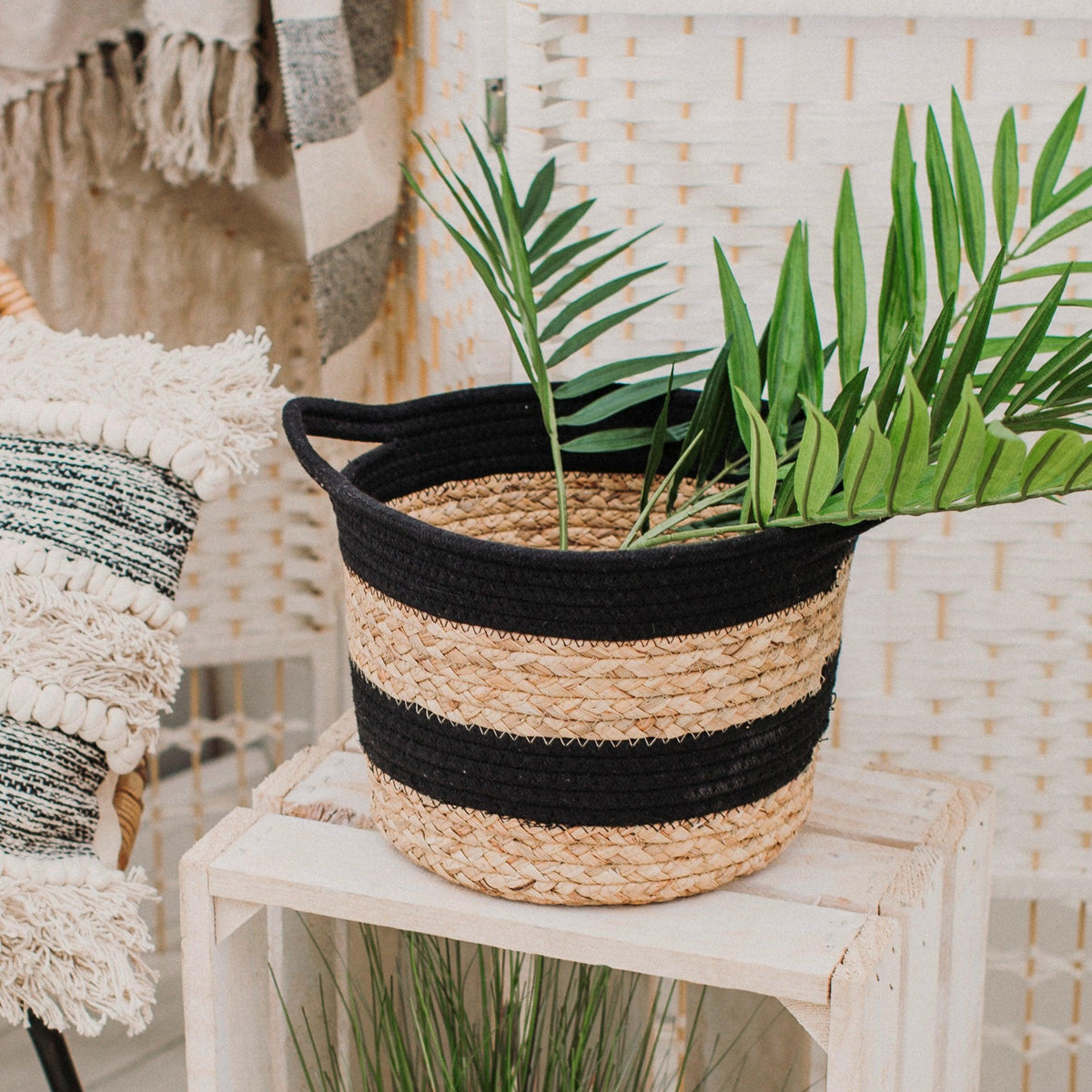 Black striped seagrass basket used as a plant cover on a small table