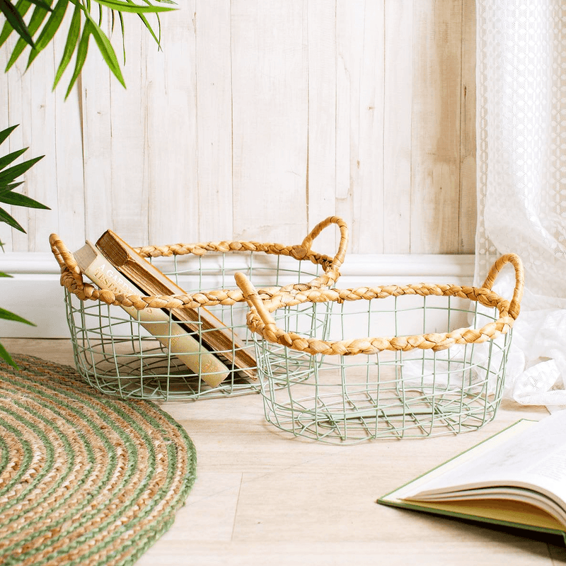 Two mint green wire baskets with woven water hyacinth rims and handles beside a chair