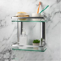 Two-tier glass bathroom wall shelf holding toiletries against a marble-effect wall
