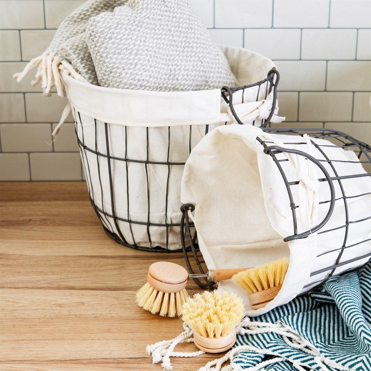 Lined grey wire storage baskets holding folded towels on a wooden surface