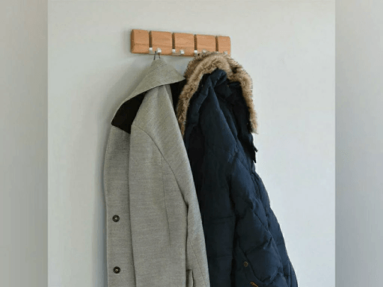 Natural wood wall-mounted coat rack holding coats