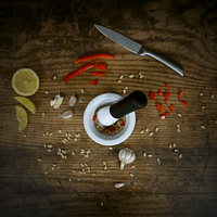 Pestle and mortar with chopped ingredients on a wooden board