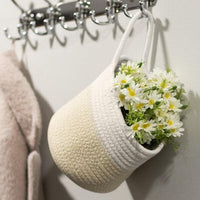 Cream and white hanging rope basket styled with flowers on a wall hook