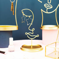 Leila gold face stand styled with earrings beside other jewellery holders