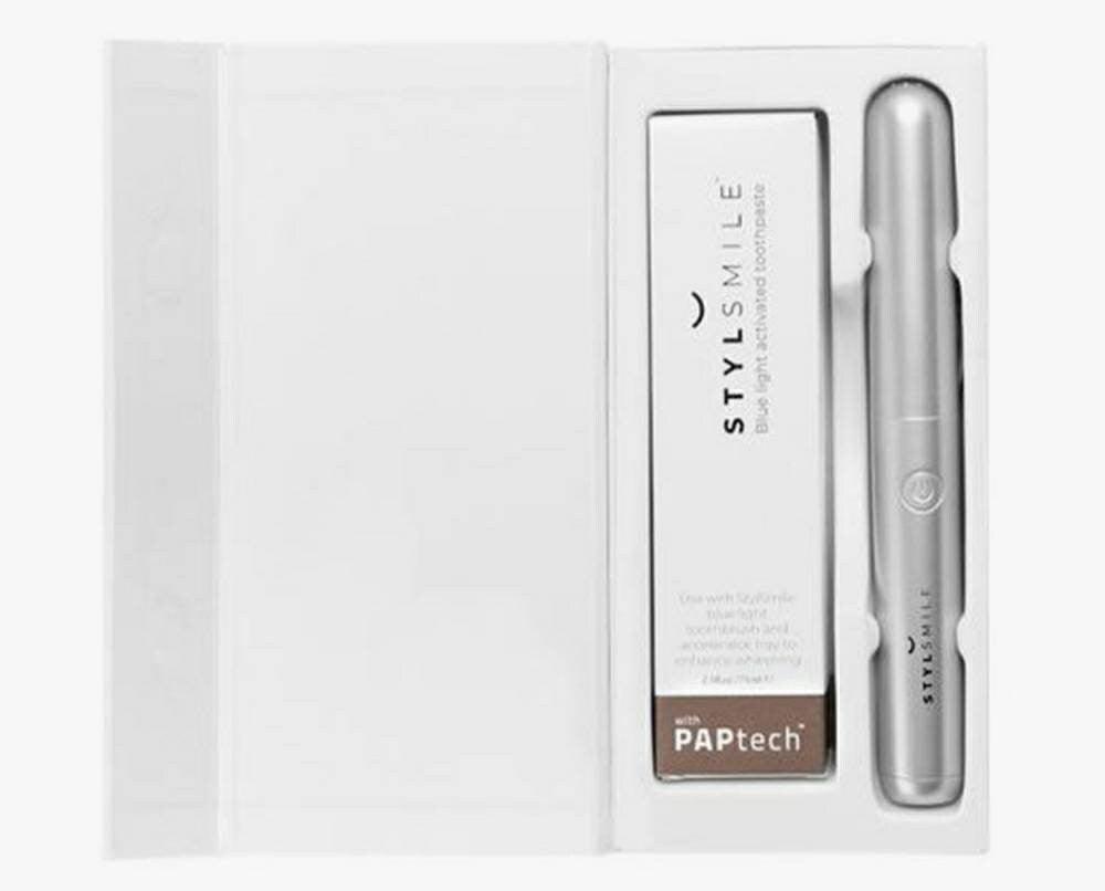 Open STYLSMILE kit showing toothpaste packaging and sonic toothbrush with travel cap
