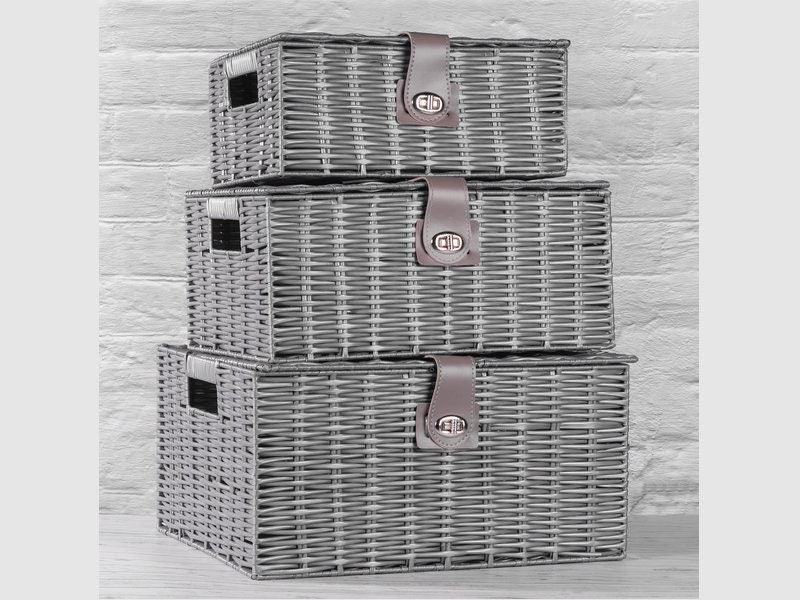 Three grey woven resin storage baskets stacked against a brick wall