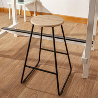 Pine seat bar stool with black metal frame beside a kitchen table